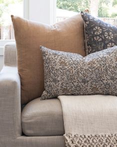 a couch with pillows on it in front of a window