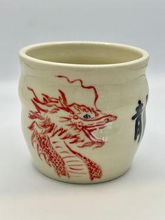 a white cup with red dragon designs on it