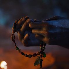 a close up of a person's hands holding a beaded bracelet with leaves on it