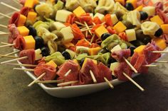 a platter filled with assorted meats and cheese on skewered toothpicks