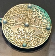 an ornate metal object with green and gold designs on it's sides, sitting on a table