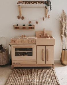 a wooden toy stove and oven in a white room with rugs on the floor