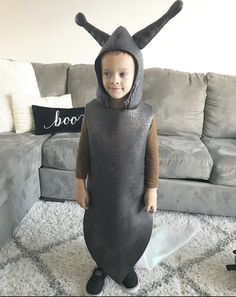 a little boy dressed up as an antelope in a living room with a gray couch