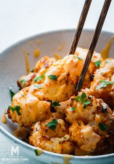 a close up of a plate of food with chopsticks in it and cheese