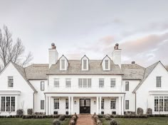 a large white house with lots of windows and brick walkway leading to the front door