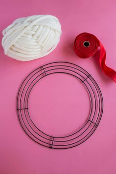 yarn, scissors and thread on a pink surface