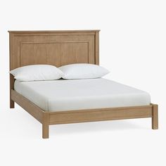 a bed with white pillows on top of it and a wooden frame around the headboard