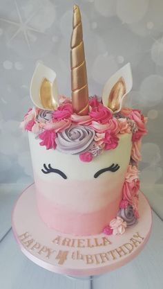 a birthday cake decorated with flowers and a unicorn's horn on top is sitting on a table