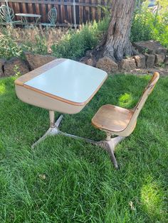 an old school desk and chair sitting in the grass