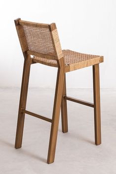 a wooden chair sitting on top of a white floor next to a brown rattan seat