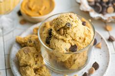 a glass bowl filled with cookies and chocolate chips on top of a white plate next to other desserts