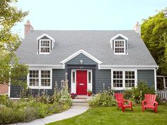 two red chairs sitting in front of a gray house