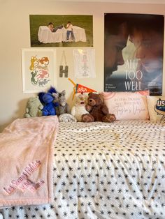 a bedroom with posters on the wall and stuffed animals on the bed in front of it