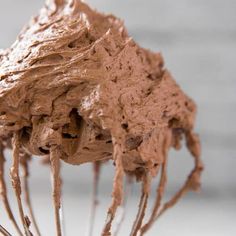 a close up of a mixer with chocolate frosting on it's head and whisk in the middle