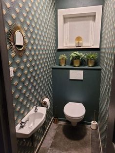 a small bathroom with green and gold wallpaper on the walls, toilet and sink