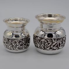 two silver vases sitting next to each other