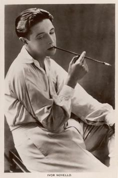 an old black and white photo of a young man holding a pipe in his mouth