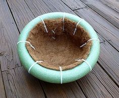 a cat bed with needles in it on a wooden decking area that has wood planks and boards