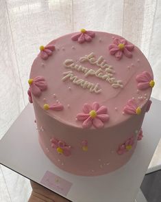 a pink cake decorated with flowers and writing