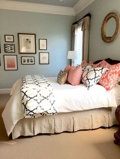 a bedroom with blue walls and pictures on the wall above the bed, along with an ottoman