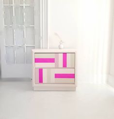 a white and pink dresser sitting on top of a floor