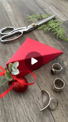 a red box with some scissors and other items on top of the wooden floor next to it