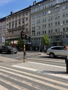 an intersection with cars and people walking on the sidewalk in front of some tall buildings