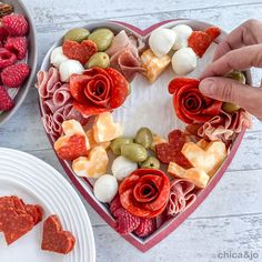 a heart shaped platter filled with meats, cheeses and fruit for valentine's day