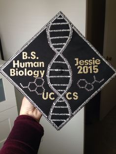 a person holding up a black and white graduation cap with the words bs human biology on it