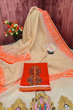 Now get ready with our latest designer jamdani collection with a pallu that comes with a machine-embroidered Durga family with lace work on the border. With all-over self-weaving work, this is a must-buy this puja season. Color: A shade of offwhite and orange color Technique: Comes with lace border and machine embroidered Durga family on the pallu Fabric: Cotton NOTE: Comes with a kalka (paisley) embroidered blouse piece Designer Cotton Silk Churidar With Embroidered Border, Wedding Cotton Silk Salwar Kameez With Embroidered Border, Off White Cotton Silk Traditional Wear With Resham Embroidery, Embroidered Off White Cotton Silk Traditional Wear, Festive White Cotton Silk Churidar, White Cotton Silk Festive Sets, Festive White Cotton Silk Set, White Cotton Silk Churidar With Pallu, White Embroidered Salwar Kameez In Cotton Silk