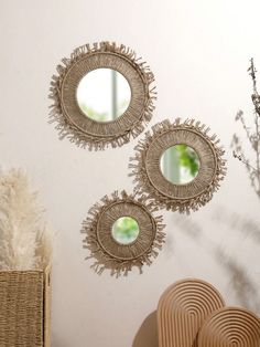 three circular mirrors hanging on the wall above a basket and wicker chair next to it