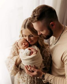 a man and woman holding a baby in their arms