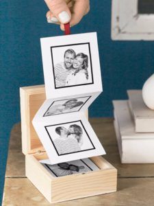 a person is placing pictures on top of a wooden box with two photos inside it