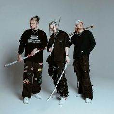 three young men standing next to each other with swords in their hands and wearing black clothing