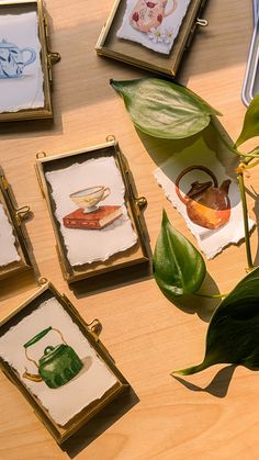 several framed pictures are sitting on a table next to a potted plant and scissors