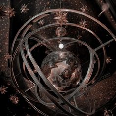 an artistic view of the earth in a circular metal structure with stars and lights around it