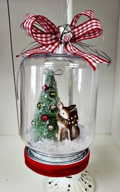 a snow globe with a christmas tree inside and a deer figurine in it