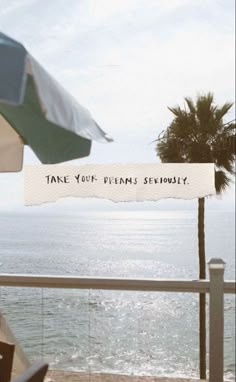 there is a sign that says take your dreams seriously next to the ocean and palm trees