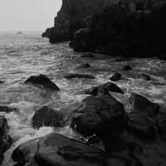 black and white photograph of waves crashing on rocks in the ocean near a rocky shore