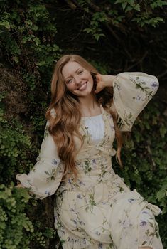 a beautiful young woman sitting on top of a tree