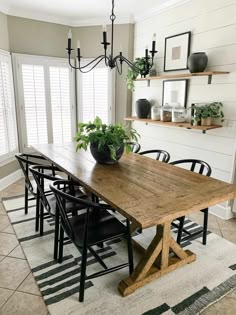 a dining room table with black chairs and a potted plant on top of it