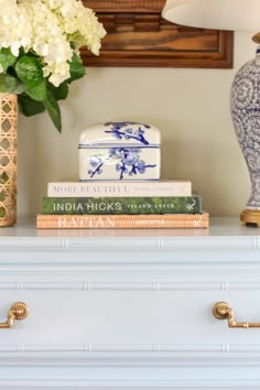 a blue and white vase sitting on top of a dresser next to a stack of books