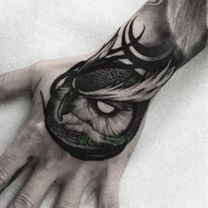 a man's hand with an owl tattoo on it