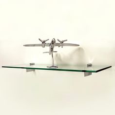 an airplane is on top of a glass shelf with two metal planes attached to it