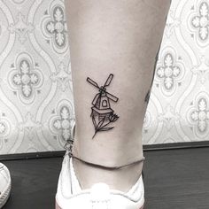 a black and white photo of a person's foot with a windmill tattoo on it