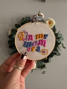 someone is holding up a small embroidery project