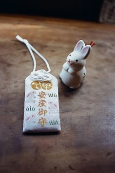 a small white rabbit figurine sitting next to a bag on a wooden table