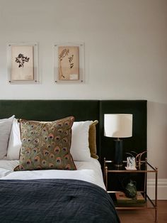 a bed with two pictures on the wall above it and a lamp next to it