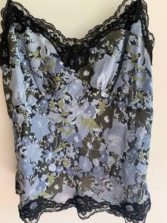 Gorgeous 100% silk lined camisole in blue gray florals with black lace trim. There is an invisible size zipper as well.  Tagged size 8 Outer shell is silk; lace and inner lining is polyester Straps are adjustable. Please use measurements as it seems to run small n my opinion! Bust flat is 17 inches underarm seam to seam.  No stretch! Length is approximately 21-22 inches as shown Strap drop as shown is 10 inches. Straps adjust.  No flaws detected but loose threads around straps and lace trim.  Wo Lace Floral Print Sleeveless Camisole, Floral Lace Sleeveless Camisole, Lace Spaghetti Strap Top With Floral Print, Lace Tops With Spaghetti Straps And Floral Print, Spring Lace Camisole With Floral Print, Floral Print Lace Camisole Top, Blue Lace Camisole For Spring, Blue Lace Fitted Camisole, Blue Fitted Lace Camisole