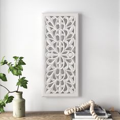 a wooden table topped with a vase filled with flowers and a white framed wall art